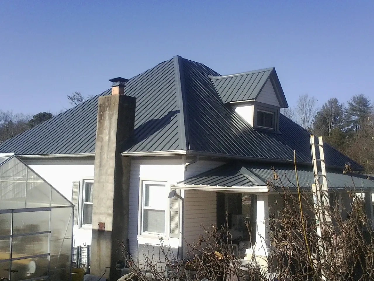 Dark blue standing seam metal roof on a white farmhouse with dormer — Slate & Tile Roof Repair by Roofing Brothers in Schaumburg