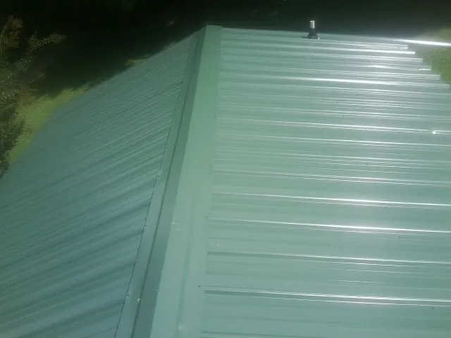 New green metal panels meeting at the ridge of a roof — Flat Roof Repair work by our crew in Schaumburg