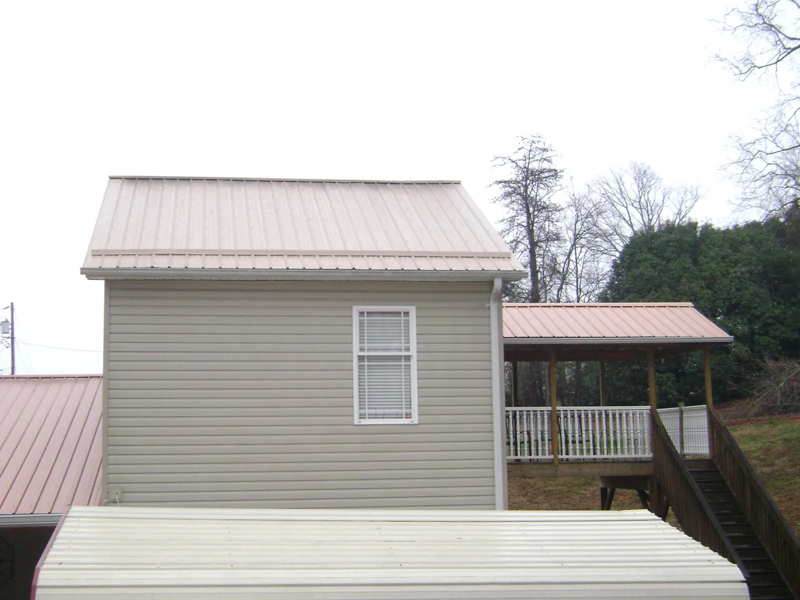 Tan metal roofs on a two story addition and attached porch, from a Roof Replacement job in Schaumburg