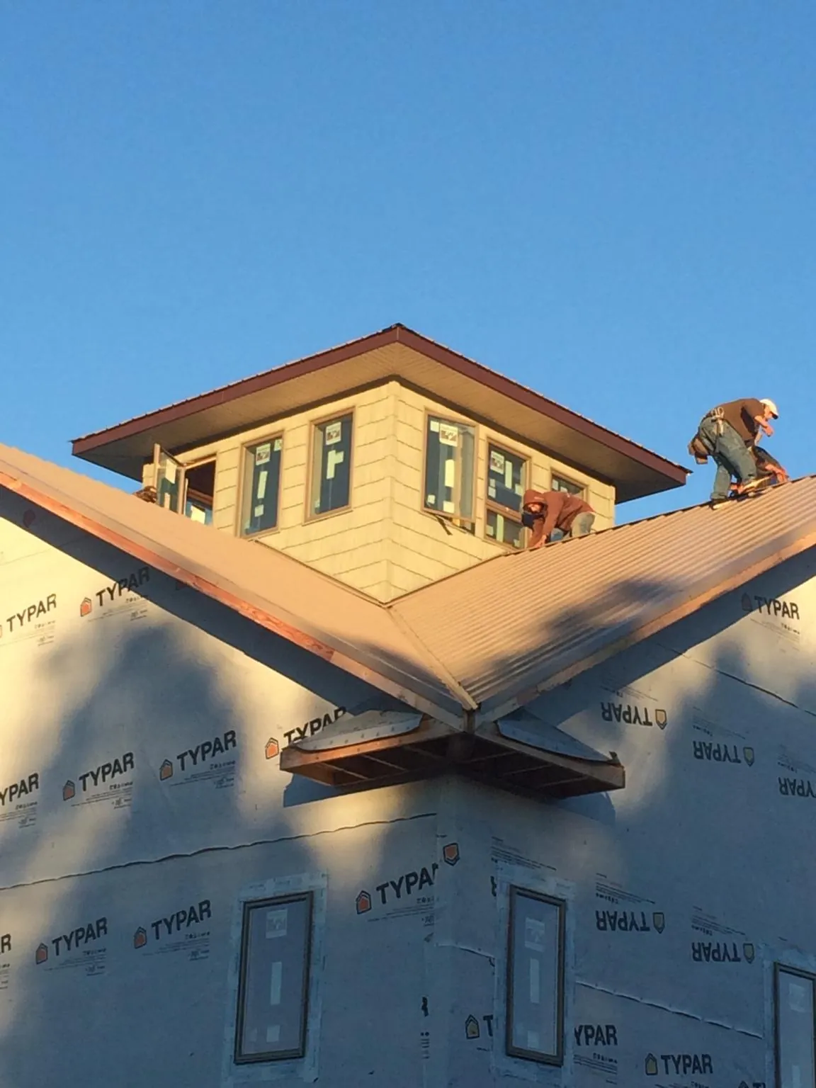 Roofers working around a rooftop cupola on a new metal roof at sunset — Roof Waterproofing in Schaumburg by Roofing Brothers